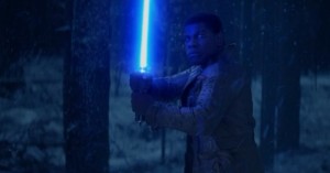 Finn holds the iconic blue lightsaber in this climactic still from Star Wars Episode VII: The Force Awakens.
